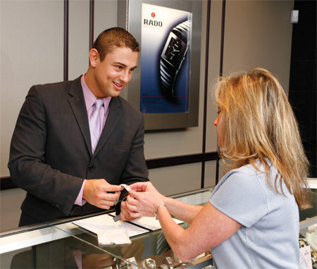 Sales Associate showing watch to a customer.